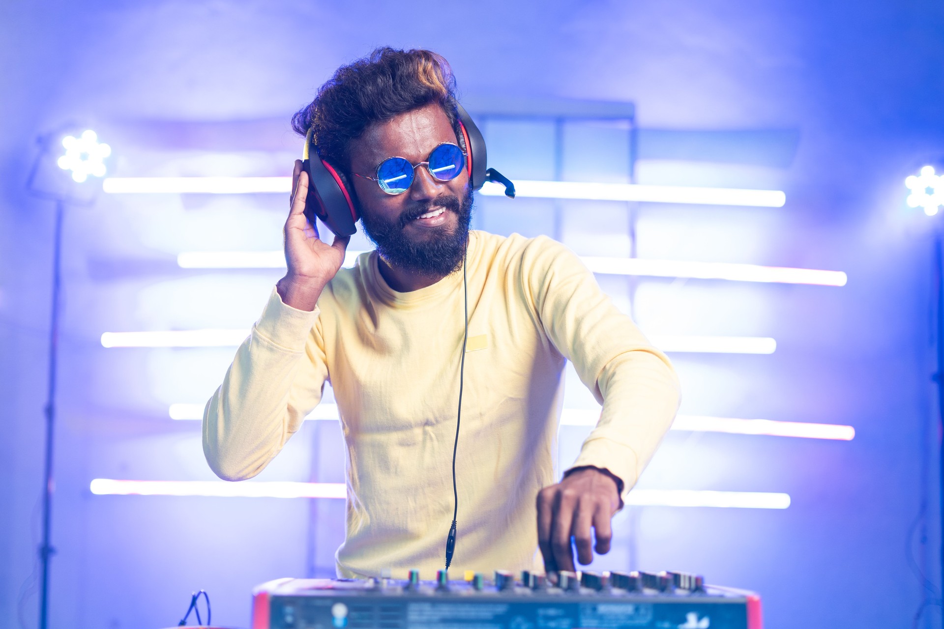 exicted dj sound device oprator with headphones by dancing at club - concept of entertainment, nightlife, music club and musician