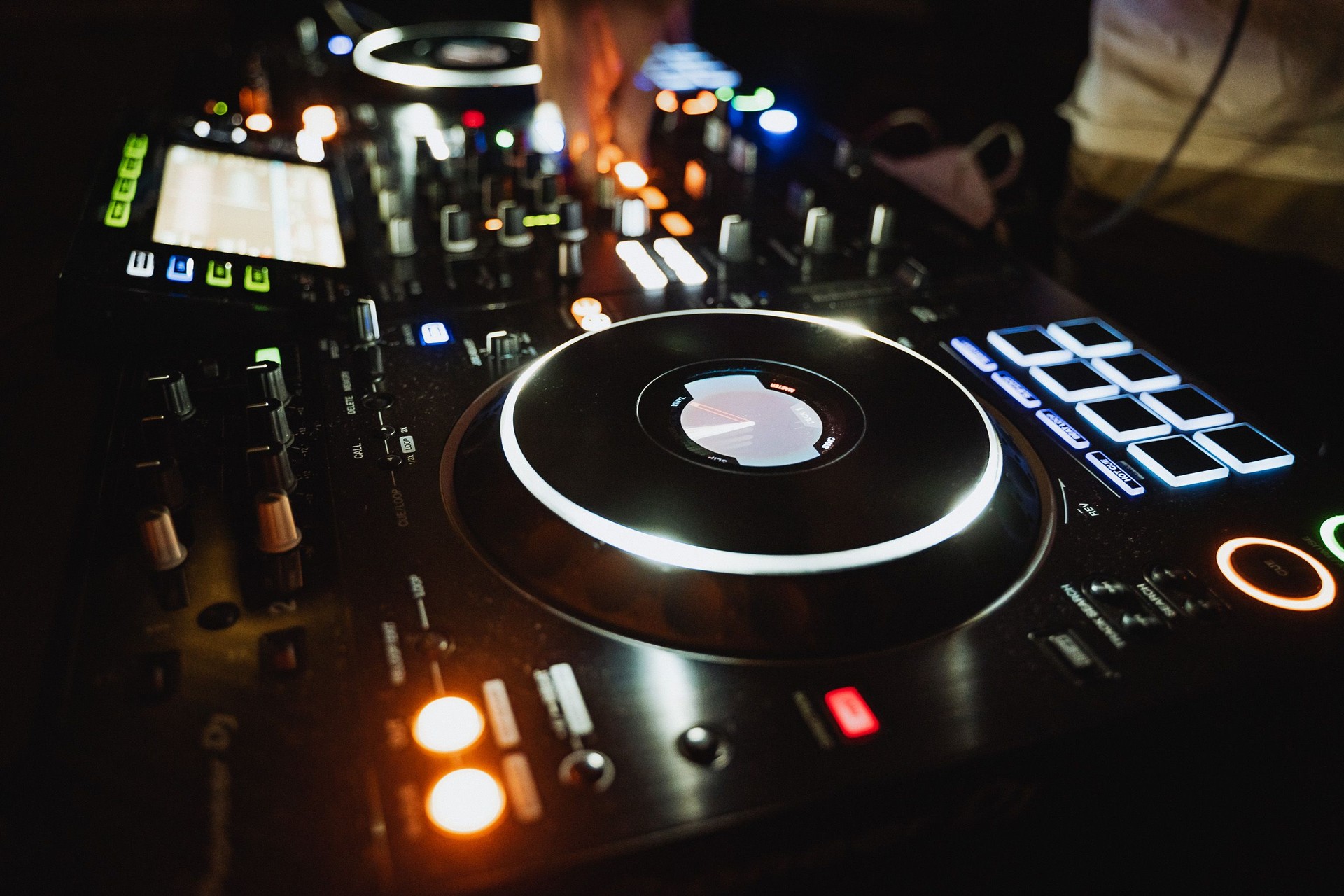 An impressive and professional DJ equipment setup featuring turntables and controllers within a vibrant nightclub setting, perfect for lively parties